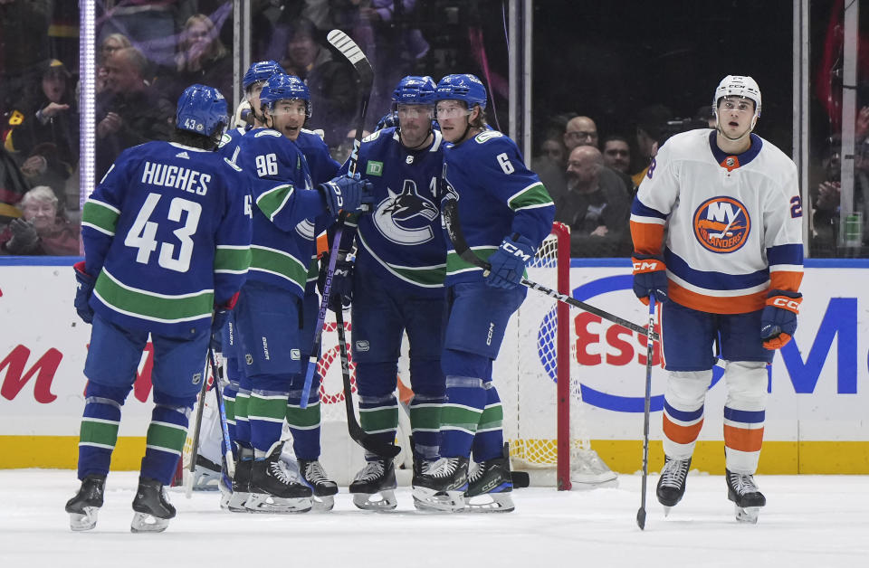 Vancouver Canucks' Andrei Kuzmenko (96), Brock Boeser (6), J.T. Miller, Quinn Hughes (43) and Elias Pettersson, back left, celebrate Boeser's goal, while New York Islanders' Alexander Romanov, right, skates past them during the second period of an NHL hockey game Wednesday, Nov. 15, 2023, in Vancouver, British Columbia. (Darryl Dyck/The Canadian Press via AP)