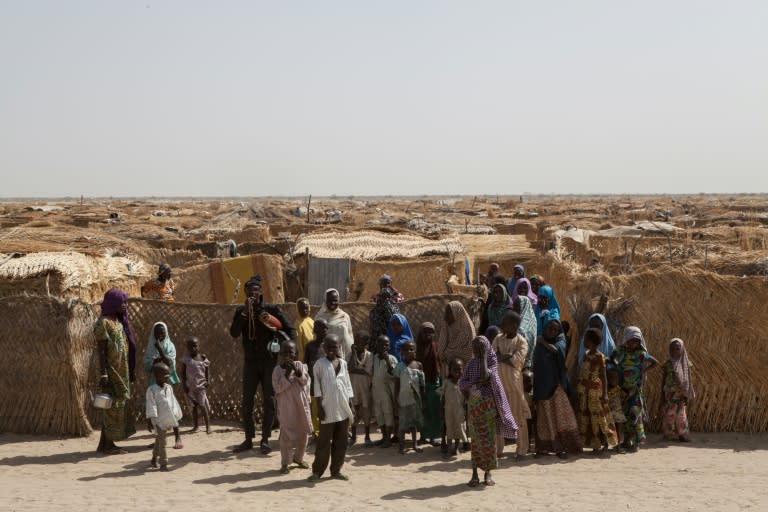 Displaced families stand at the main gate of a camp for internally displaced people in Monguno district of Borno State, northeast Nigeria on February 14, 2017