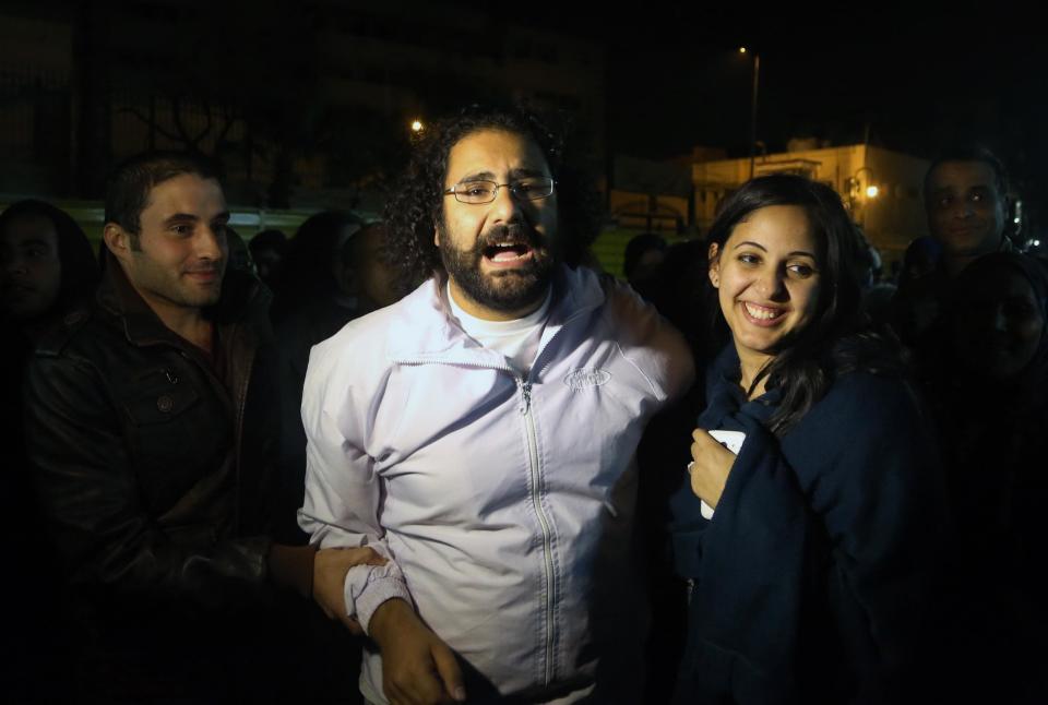 Alaa Abdel-Fattah, center in white, a prominent activist and a leading figure in the 2011 uprising against Egyptian autocrat Hosni Mubarak, is welcomed by his wife after he was released from the main central security office in Cairo, Egypt, Sunday, March 23, 2014. Abdel-Fattah was arrested from his home on Nov. 28, 2013, and he and his wife accuse police of attacking them during the arrest. Egyptian court on Sunday ordered the release on bail pending trial of Abdel-Fattah charged with breaking a new law that heavily restricts protests, after he spent nearly four months in jail. (AP Photo/Roger Anis, El Shorouk Newspaper) EGYPT OUT