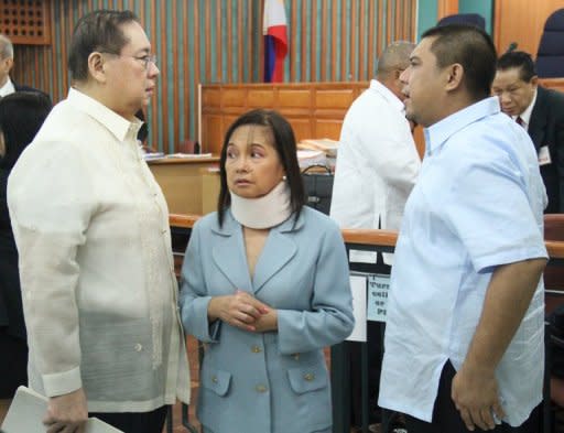 Philippine former president Gloria Arroyo (C) talks to her husband Mike (L) and son Mikey (R) prior to her arraignment at the anti-graft court in Manila in April 2012. Arroyo is charged with "electoral sabotage", a crime punishable with life in jail, for allegedly conspiring with a feared political warlord to rig the 2007 senatorial elections