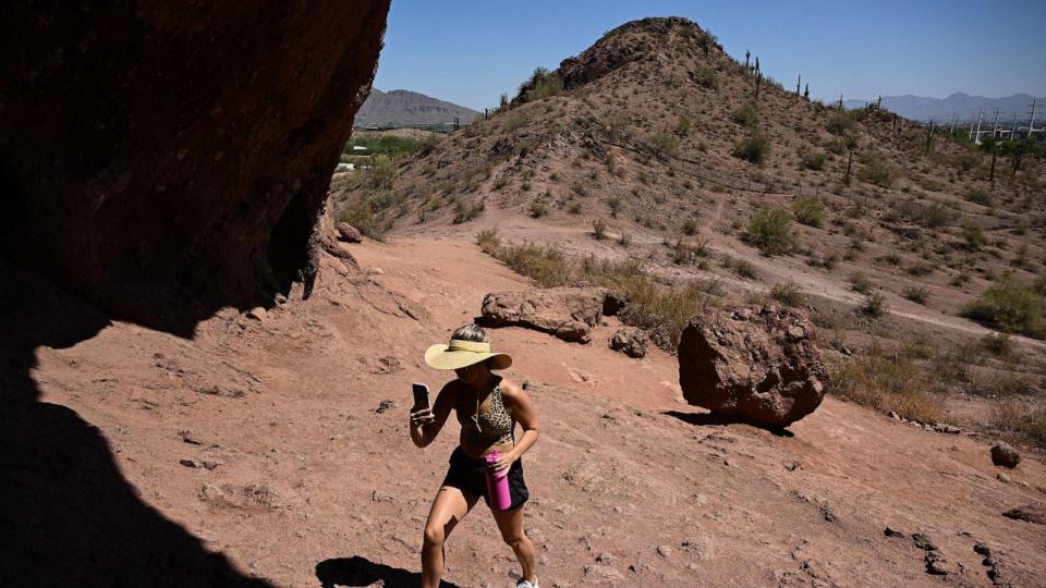 PHOTO: A visitor from Canada carries water while hiking up the Hole In The Rock trail during a record heat wave in Phoenix, Arizona, on July 19, 2023. (Patrick T. Fallon/AFP via Getty Images)