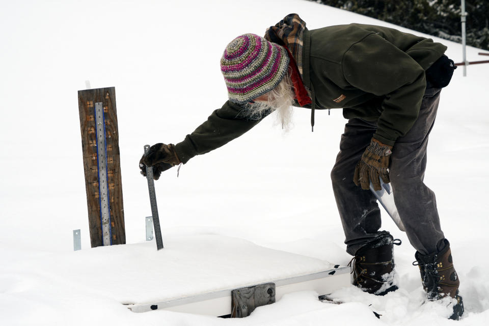 Billy Barr measures the depth of new snow that has fallen onto his snow board Wednesday, March 13, 2024, in Gothic, Colo. So-called “citizen scientists” like Barr have long played important roles in gathering data to help researchers better understand the environment. His once hand-recorded measurements have informed numerous scientific papers and helped calibrate aerial snow sensing tools. (AP Photo/Brittany Peterson)