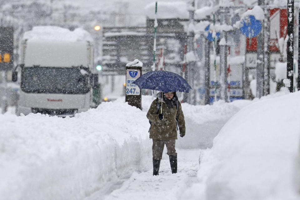 A woman makes her way through heavy snow Tuesday, Dec. 20, 2022 in Uonua, Niigata prefecture, northern Japan.(Kyodo News via AP)