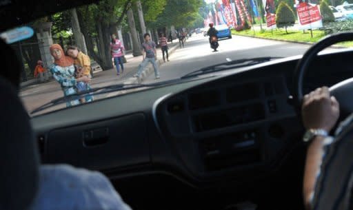 Traffic jockeys wait for commuters along a street in Jakarta. They line the main arteries of the Indonesian capital every weekday, offering to ride in private vehicles during rush hours, when cars are obliged to carry at least three passengers on key stretches