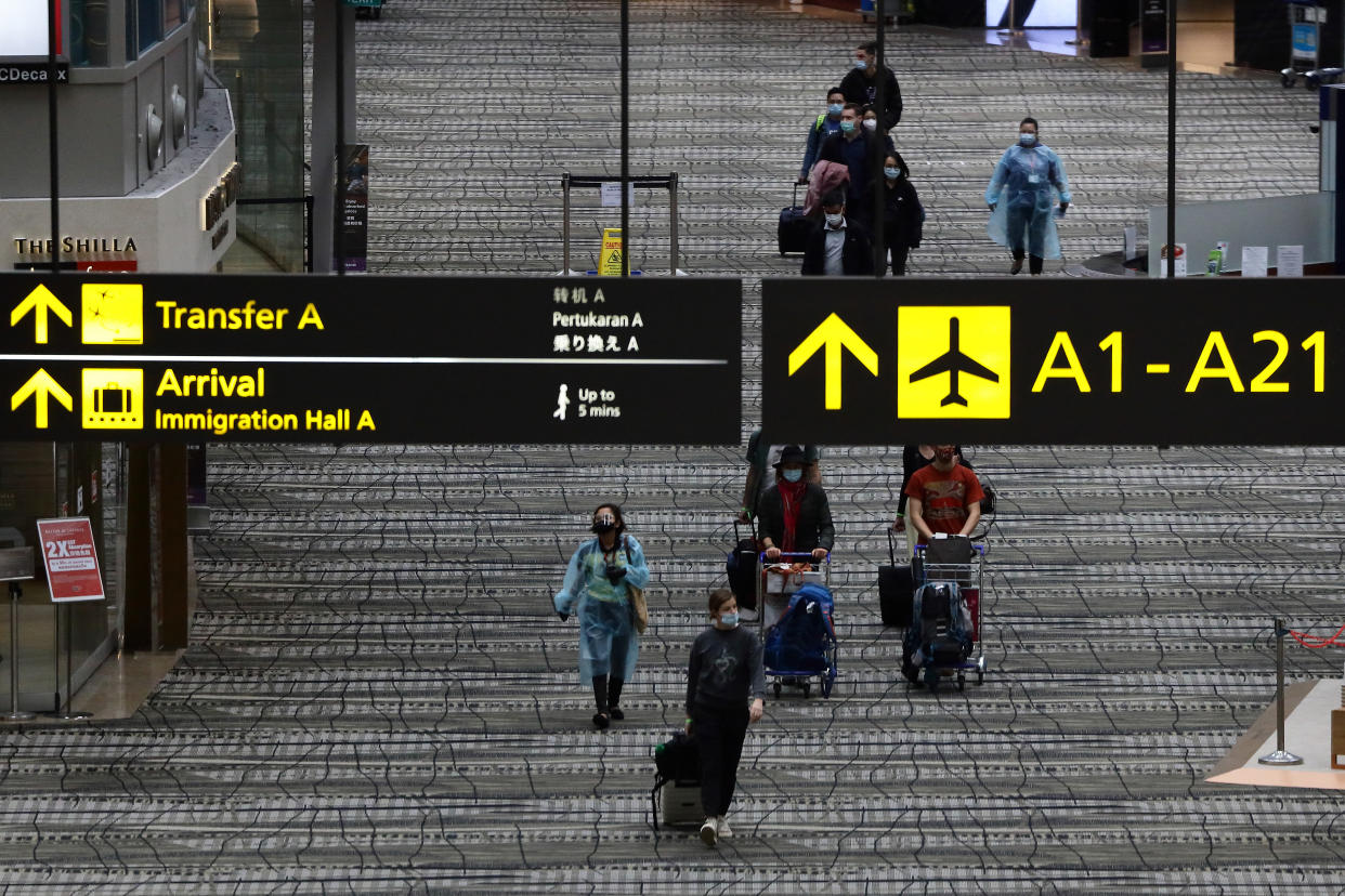 SINGAPORE - DECEMBER 15: Travellers wearing protective mask walk along the transit area of Changi International Airport terminal on December 15, 2020 in Singapore. From mid-January, Singapore will allow a limited number of business travellers from any country to visit up to 14 days under a new segregated travel lane arrangement where they will be housed within dedicated facilities undergoing regular testing and observe all safety measurement management measures. As of 14 December, the Ministry of Health confirmed 5 new imported COVID-19 cases with no cases in the wider community bringing the country's total to 58,325. (Photo by Suhaimi Abdullah/Getty Images)