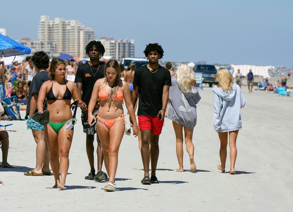 Spring breakers walk along the shore in New Smyrna Beach, Wednesday, March 20, 2024.