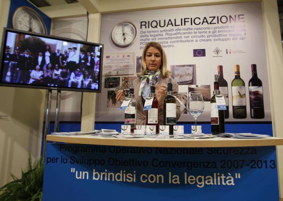 A woman prepares bottles of wine in a 'Pon sicurezza project' stand at the 46th edition of the annual International Wine and Spirits Exhibition "Vinitaly", in Verona, northern Italy, Monday, March 26, 2012. The prize-winning Sicilian white wine Grillo is blended from native grape varieties grown at an altitude of 600 meters (1,900-feet.) But there's an additional appeal that escapes the palate: the vineyard have been cultivated on lands once held by the Mafia. (AP Photo/Luca Bruno)
