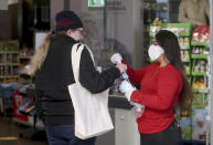 Supermarket employees distribute protective masks to customers in Vienna, Austria, Wednesday, April 1, 2020. In Austria protective masks should be worn in shops from Wednesday on. The Austrian government has moved to restrict freedom of movement for people, in an effort to slow the onset of the COVID-19 coronavirus. The new coronavirus causes mild or moderate symptoms for most people, but for some, especially older adults and people with existing health problems, it can cause more severe illness or death. (AP Photo/Ronald Zak)