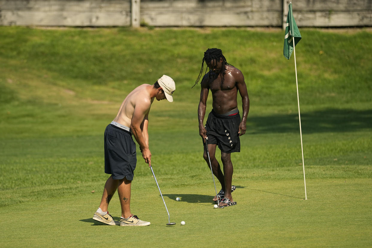 Brant Gomez, left, and Quinton Riley, right, play shirtless golf