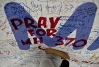 A file photo shows a Malaysia Airlines employee writing prayers for passengers onboard missing flight MH370 at Kuala Lumpur International Airport