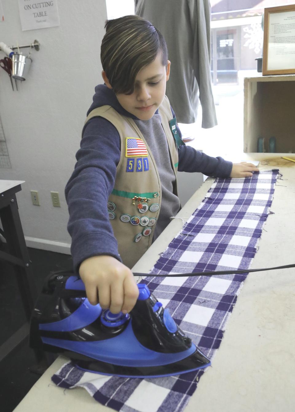 Boy Scout Aaron Jimenez irons fabric before it's made into a joey sack for Australian wildlife that survived the Australian fires. Aaron was part of a group who started the sewing project at the Redding Fashion Alliance on Thursday, Jan. 9, 2020.