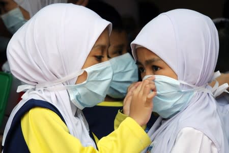 Students cover their faces with masks at a school as haze shrouds Kuala Lumpur