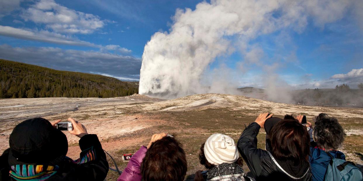 FILE - In this May 21, 2011 file photo, tourists photograph Old Faithful erupting on schedule late in the afternoon in Yellowstone National Park, Wyo. On Tuesday, March 24, 2020 the National Park Service announced that Yellowstone and Grand Teton National Parks would be closed until further notice, and no visitor access will be permitted to either park..(AP Photo/Julie Jacobson, File)