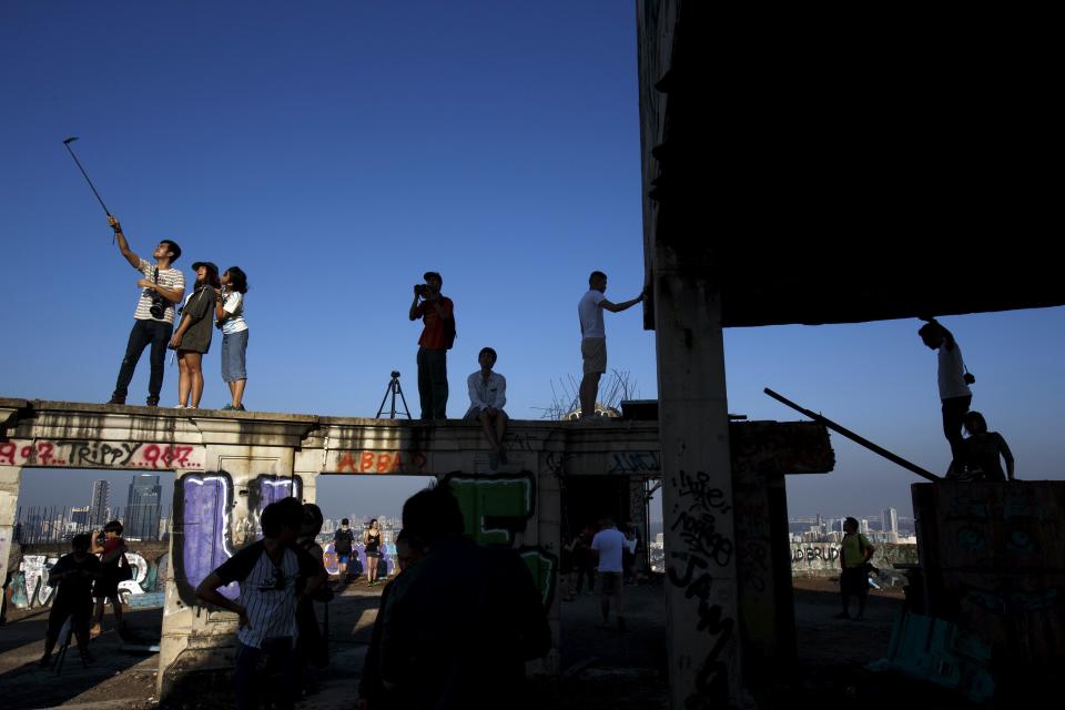 Visitors enjoy the roof top of an abandoned building in Bangkok. The abandoned building, known as Sathorn Unique, dubbed the 'ghost tower' was destined to become one of Bangkok's most luxurious residential addresses but construction was never completed as the Thai economy was hit during the 1997 Asian financial crisis. Now, many travellers visit and explore the 49-story skyscraper. (REUTERS/Athit Perawongmetha)