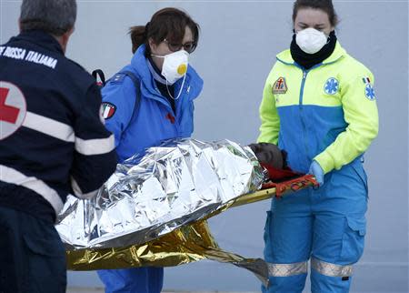 A migrant is carrried by rescuers as he arrives at the Sicilian port of Augusta near Siracusa March 21, 2014. REUTERS/Antonio Parrinello