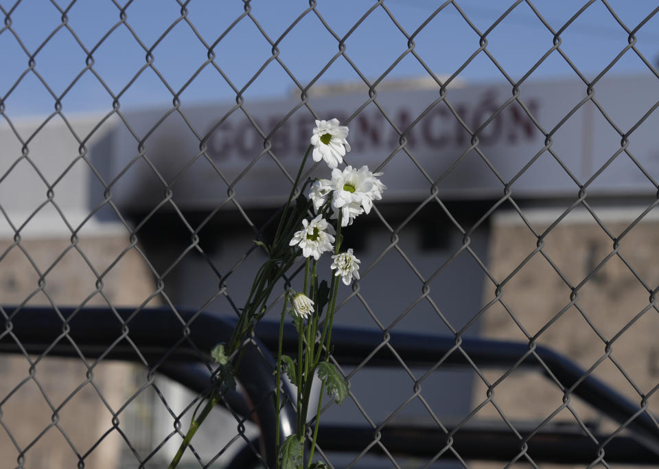 Wilted flowers hang from the fence outside an immigration detention center where a fire killed dozens in Ciudad Juarez, Mexico, Tuesday, March 28, 2023. According to Mexican President Andres Manuel Lopez Obrador, migrants fearing deportation set mattresses ablaze at the center, starting the fire. (AP Photo/Fernando Llano)