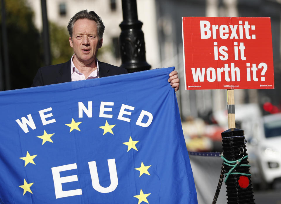 A pro-EU demonstrator holds up an EU flag to oncoming traffic outside the Palace of Westminster as the British government holds a cabinet meeting on Brexit inside 10 Downing Street, London, Tuesday, Oct. 16, 2018. The Brexit agreement must be sealed in the coming weeks to leave enough time for relevant parliaments to ratify it, but talks continue, particularly over how to ensure no physical border dividing the UK from Northern Ireland and the EU member state of Ireland. (AP Photo/Alastair Grant)