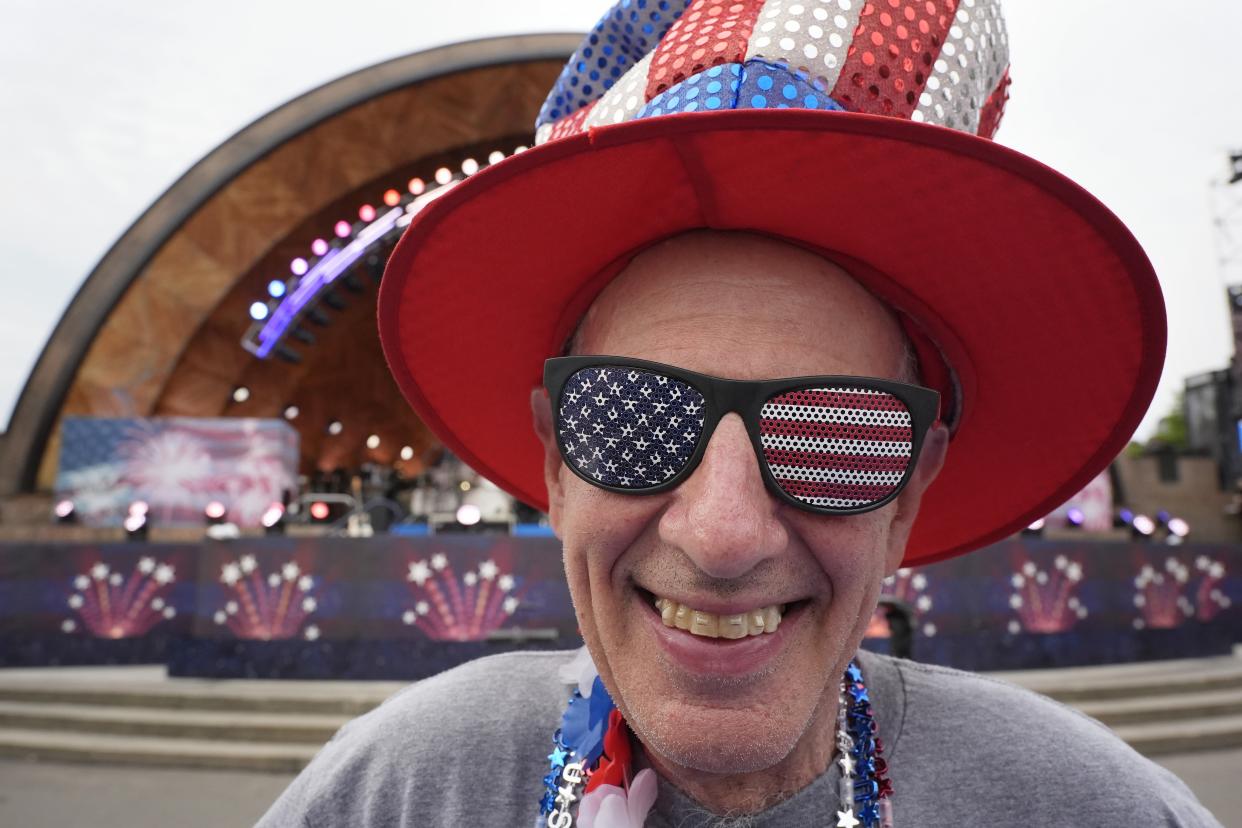 A man wearing stars-and-stripes-themed sunglasses and hat, with the Hatch Shell in the background.
