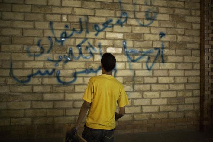 A supporter of ousted Egyptian President Mohammed Morsi paints graffiti on the wall of a Coptic Church in Assiut, Upper Egypt, Tuesday, Aug. 6, 2013. Islamists may be on the defensive in Cairo, but in Egypt's deep south they still have much sway and audacity: over the past week, they have stepped up a hate campaign against the area's Christians. Blaming the broader Coptic community for the July 3 coup that removed Islamist president Mohammed Morsi, Islamists have marked Christian homes, stores and churches with crosses and threatening graffiti. Arabic graffiti reads, "Boycott the Christian dogs." (AP Photo/Manu Brabo)