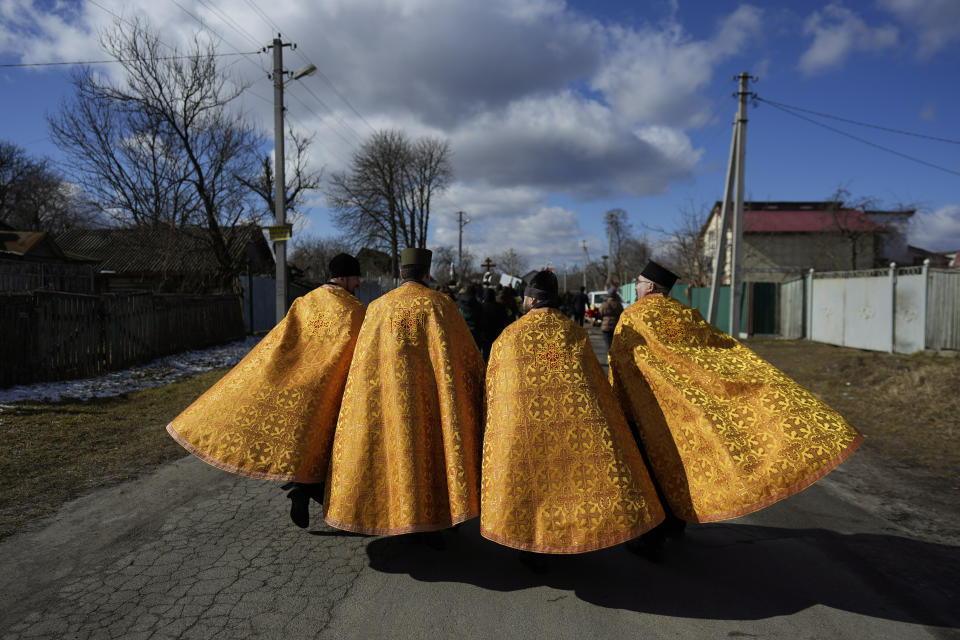 Priests walk to the cemetery during the funeral of Vladyslav Bondarenko 26, in Kozyntsi, near Kyiv, Ukraine, Monday, March 6, 2023. Bondarenko, a paratrooper of airmobile brigade, died near Bakhmut on Feb 26. (AP Photo/Thibault Camus)