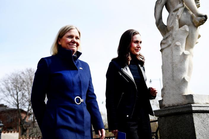 Swedish Prime Minister Magdalena Andersson and Finnish Prime Minister Sanna Marin walk together outside, next to a marble statue.