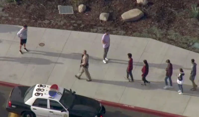 A law enforcement official leads students at the scene of a shooting at Saugus high school in Santa Clarita