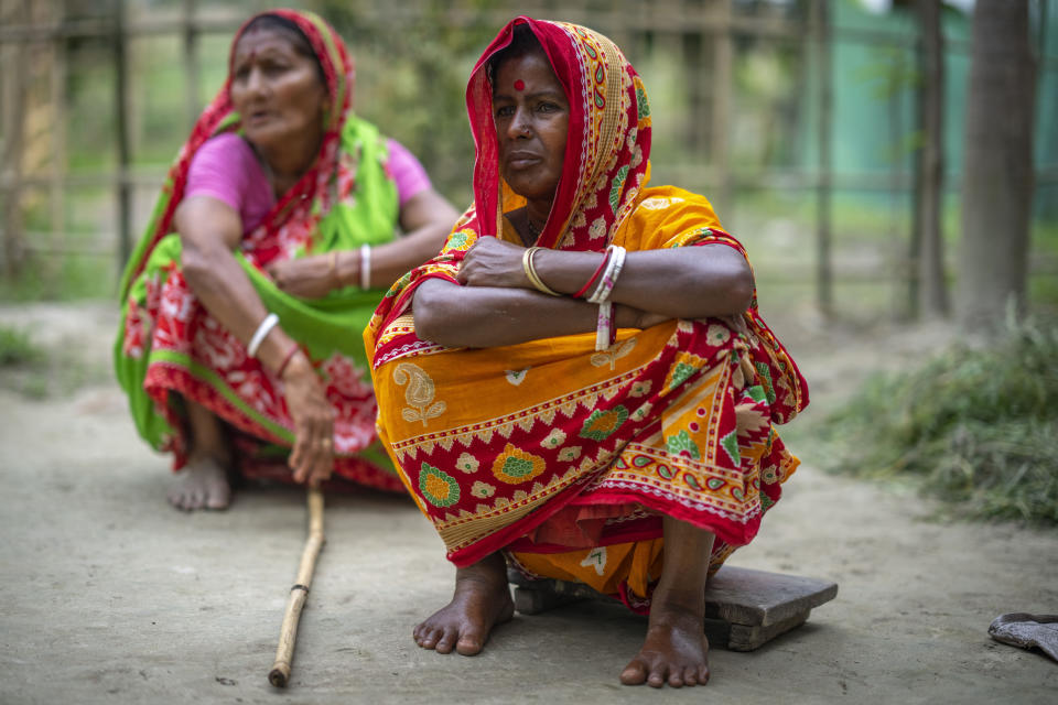 Two members of the Biswas family, the majority of whom have not been able to prove their Indian citizenship, look on as their relatives talk to the Associated Press in Murkata village, north eastern Assam state, India, April 15, 2023. Nearly 2 million people, or over 5% of Assam's population, could be stripped of their citizenship unless they have documents dating back to 1971 that show their ancestors entered the country legally from neighboring Bangladesh. (AP Photo/Anupam Nath)