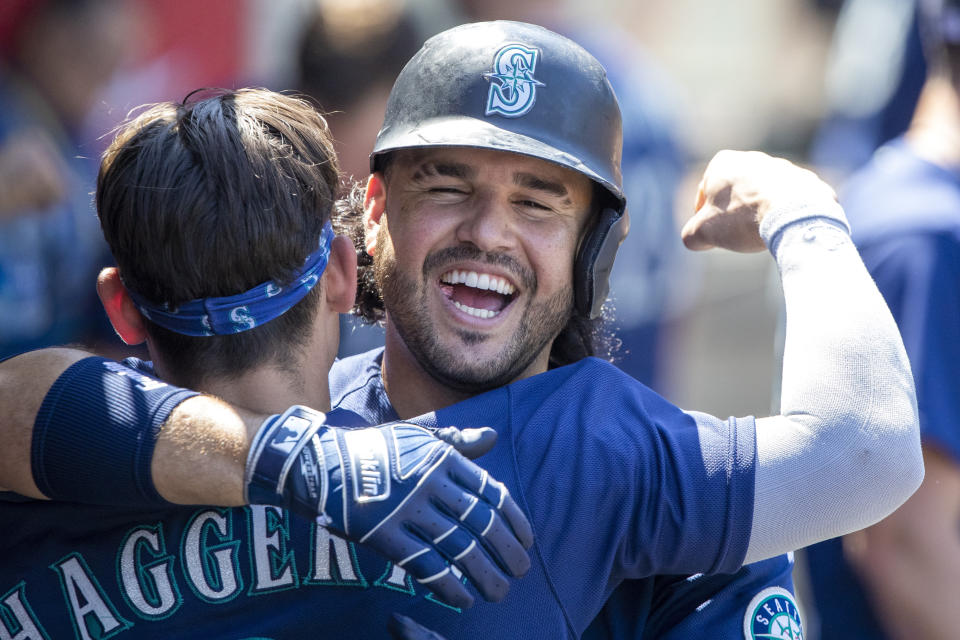 Seattle Mariners' Eugenio Suarez, right, hugs Sam Haggerty in the dugout to celebrate Suarez's two-run home run against the Los Angeles Angels during the fifth inning of a baseball game in Anaheim, Calif., Wednesday, Aug. 17, 2022. (AP Photo/Alex Gallardo)