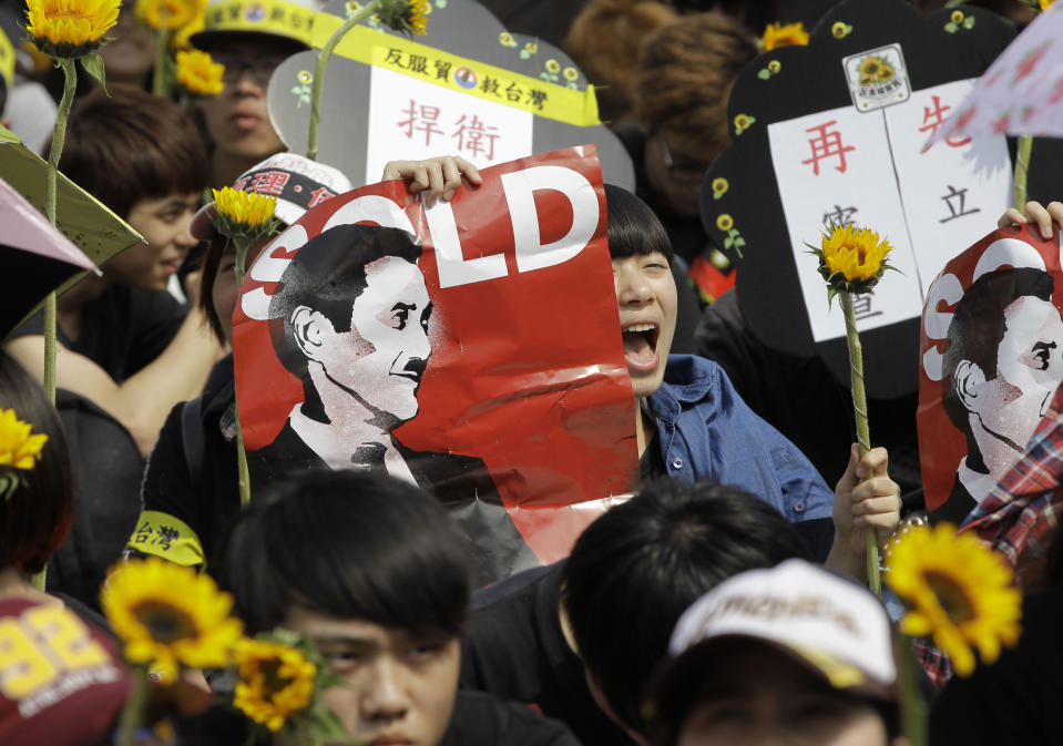 A protester holds a banner depicting Taiwanese President Ma Ying-jeou as Hitler while shouting slogans denouncing the controversial China Taiwan trade pact during a massive protest in front of the Presidential Building in Taipei, Taiwan, Sunday, March 30, 2014. Over a hundred thousand protesters gathered in the demonstration against the island's rapidly developing ties with the communist mainland. (AP Photo/Wally Santana)