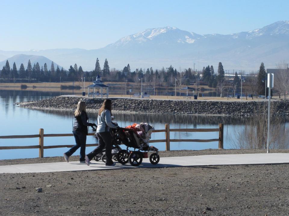 Women push strollers on the 2-mile loop trail surrounding the Sparks Marina, where all of the fish have died over the past month _ an estimated total of 100,000 trout, bass and catfish _ on Friday, Jan. 17, 2014, in Sparks, Nev. Scientists say a sudden cold spurt in December likely caused a violent ``turnover'' of the 77-acre, man-made lake's waters that sucked out almost all the oxygen and killed the fish. (AP Photo/Scott Sonner).