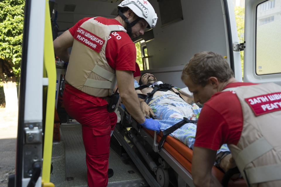 Volunteers of Ukrainian Red Cross emergency move a wounded man to an ambulance to transport him from one hospital to another, in Mykolaiv, Ukraine, Tuesday, Aug. 9, 2022. (AP Photo/Evgeniy Maloletka)