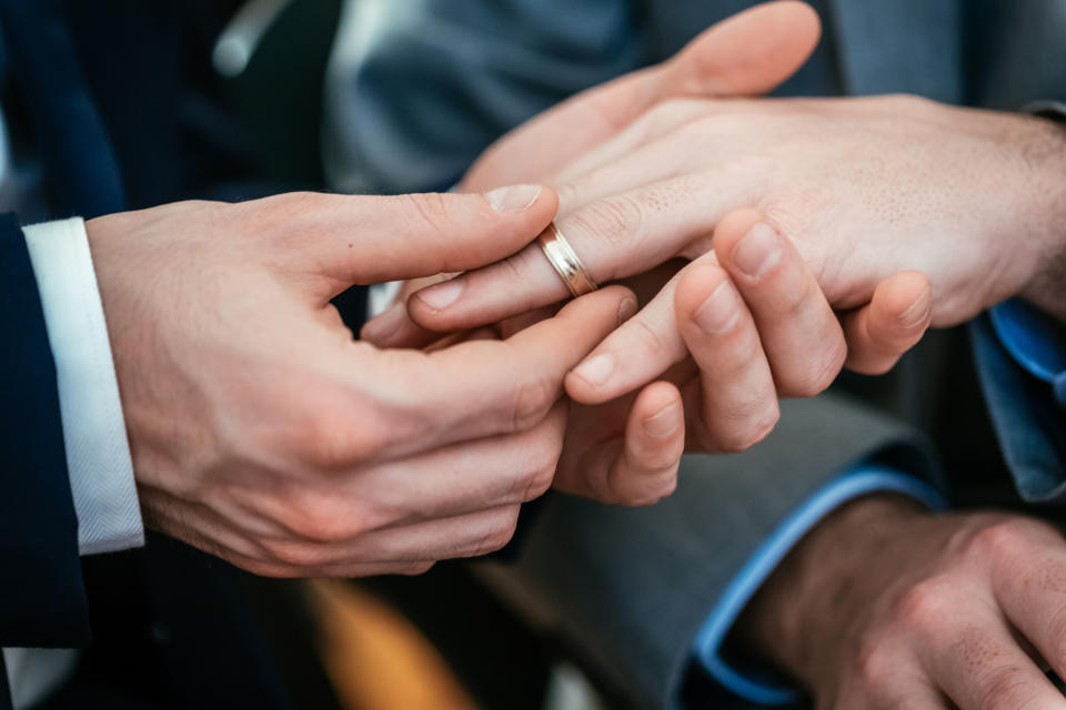 Person sliding a wedding ring onto another person's finger