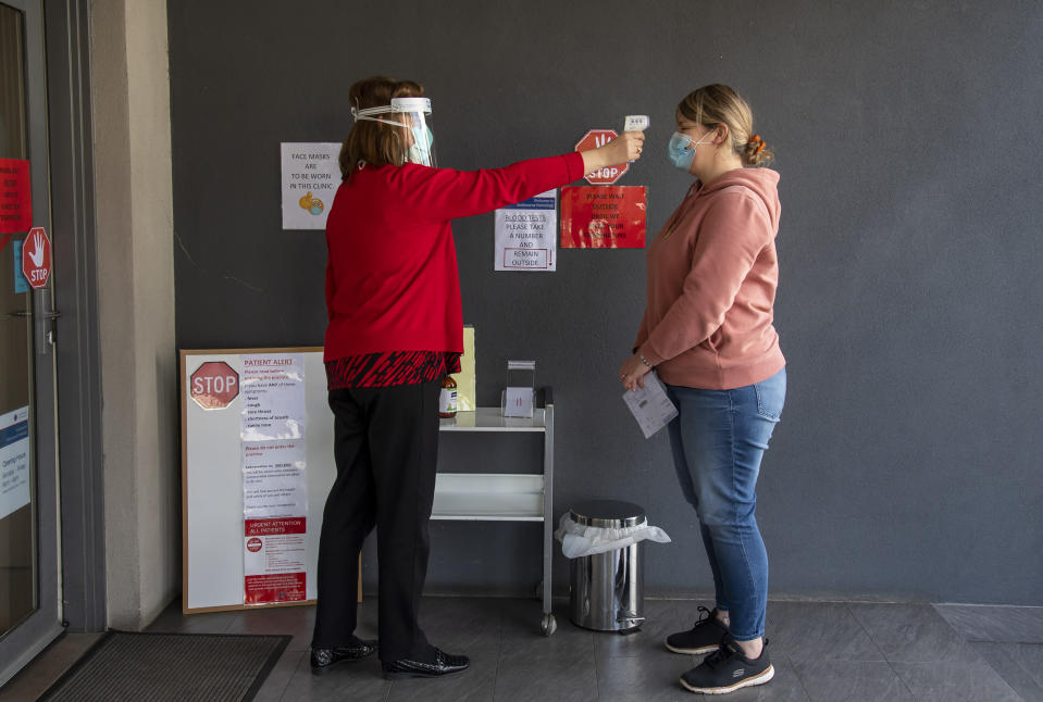 A patient has her temperature checked at a medical clinic during lockdown due to the continuing spread of the coronavirus in Melbourne, Thursday, Aug. 6, 2020. Victoria state, Australia's coronavirus hot spot, announced on Monday that businesses will be closed and scaled down in a bid to curb the spread of the virus. (AP Photo/Andy Brownbill)