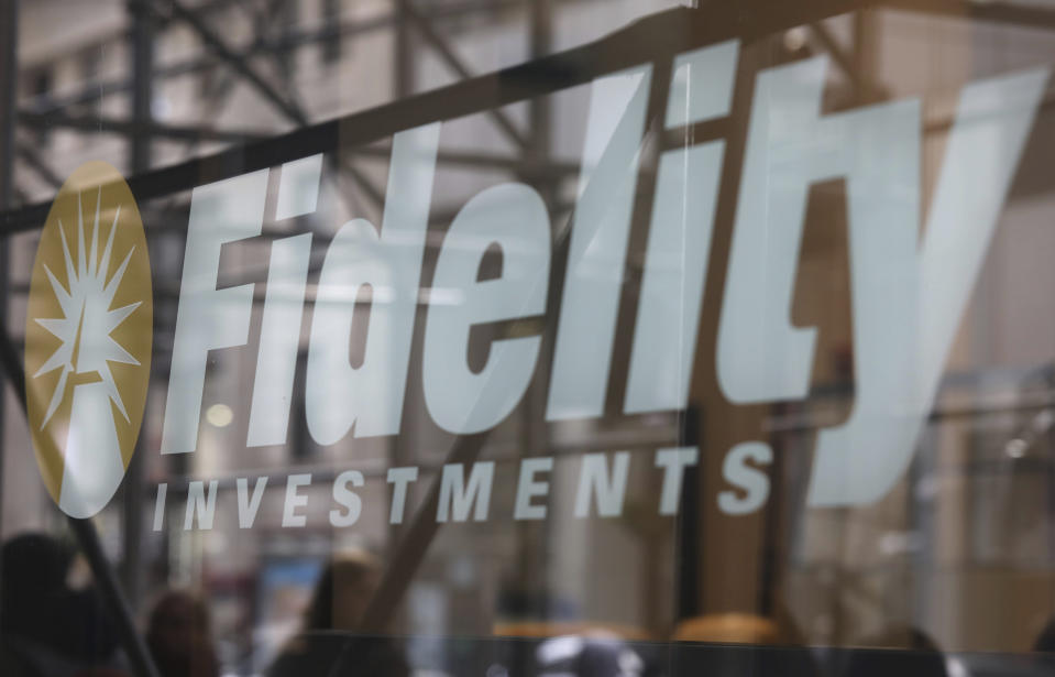 In this March 28, 2019, photo people are reflected in a window as they walk by a Fidelity Investments office in New York. (AP Photo/Jenny Kane)