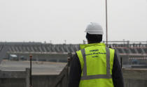 A worker stands on the construction site of the project in Venice, Italy, Friday, Nov. 29, 2019. The system of moveable under water barriers, dubbed Moses, has been beset by corruption, cost overruns and delays. Projected at 1.8 billion euros and to be completed by 2011, the project has cost 5.5 billion euros and won’t be operational before the end of 2021. (AP Photo/Antonio Calanni)