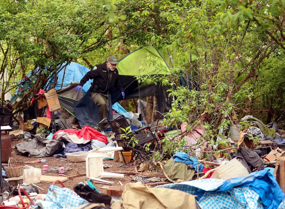 Kitsap County Sheriff's Office Community Resource Officer Deputy Montague makes his way through a litter-strewn campsite after checking to make sure the tent was empty at Veterans Memorial Park in Port Orchard on Friday.