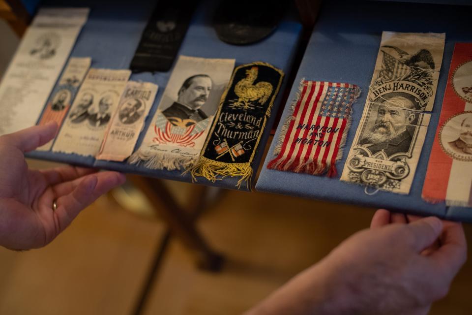 A man's hands are seen at the base of a display of ribbons and badges.