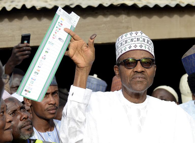 Mohammadu Buhari holds his ballot paper prior to casting his vote at a polling station in Katsina State on March 28, 2015