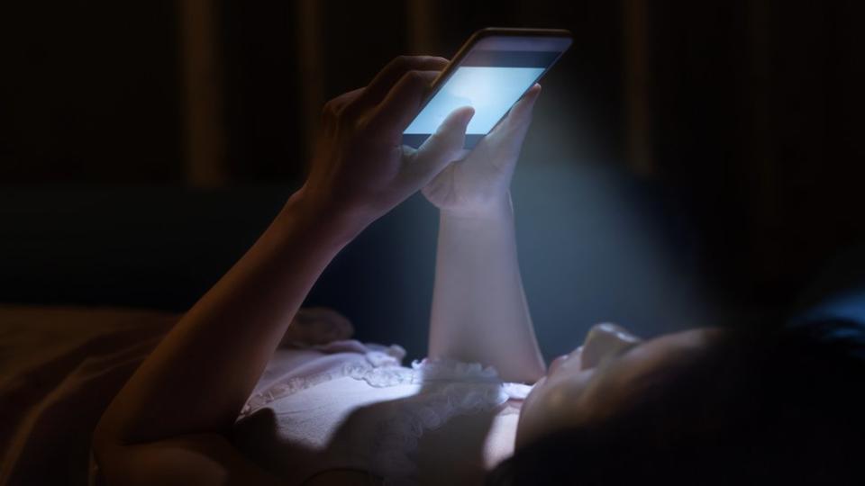 Niña viendo su teléfono en la noche