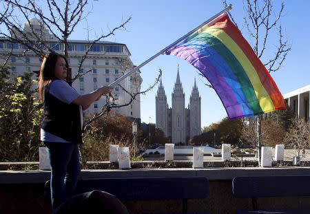 Sandy Newcomb stands with a flag near the Salt Lake Temple after members of The Church of Jesus Christ of Latter-day Saints mailed their membership resignation to the church in Salt Lake City, Utah November 14, 2015. REUTERS/Jim Urquhart