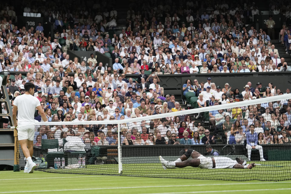 Spain's Carlos Alcaraz, left, looks over at Francis Tiafoe of the United States who fell during their third round match at the Wimbledon tennis championships in London, Friday, July 5, 2024. (AP Photo/Alberto Pezzali)