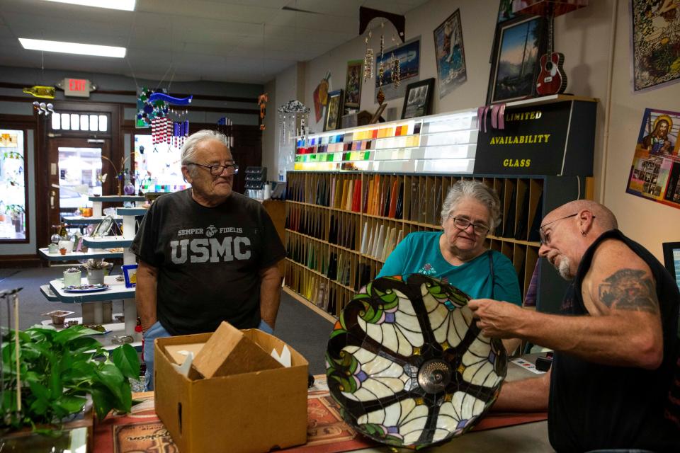 Bernie Evans, owner of Bernie and Max Stained Glass Studio, talks to Joe and Nancy Malorgio, of Waverly, about repairing the stained glass lamp shade for their antique lamp in the display room at Bernie and Max Stained Glass Studio on Sept. 22, 2022 in Chillicothe, Ohio. Bernie has been working with stained galls for the last 17 years. The studio restores and creates stained glass windows, doors and create unique pieces at the studio in downtown Chillicothe. 