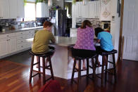 Jennifer Osgood, center, helps her children Lily, 7, right, and Noah, 12, left, while studying at the kitchen counter in the family's home, Tuesday, July 20, 2021, in Fairfax, Vt. The Osgood children will continue to be homeschool this upcoming school year. As the pandemic took hold across the United States in the spring of 2020, it brought disruption and anxiety to most families. Yet some parents are grateful for one consequence: they are now opting to homeschool their children even as schools plan to resume in-person classes. (AP Photo/Charles Krupa)