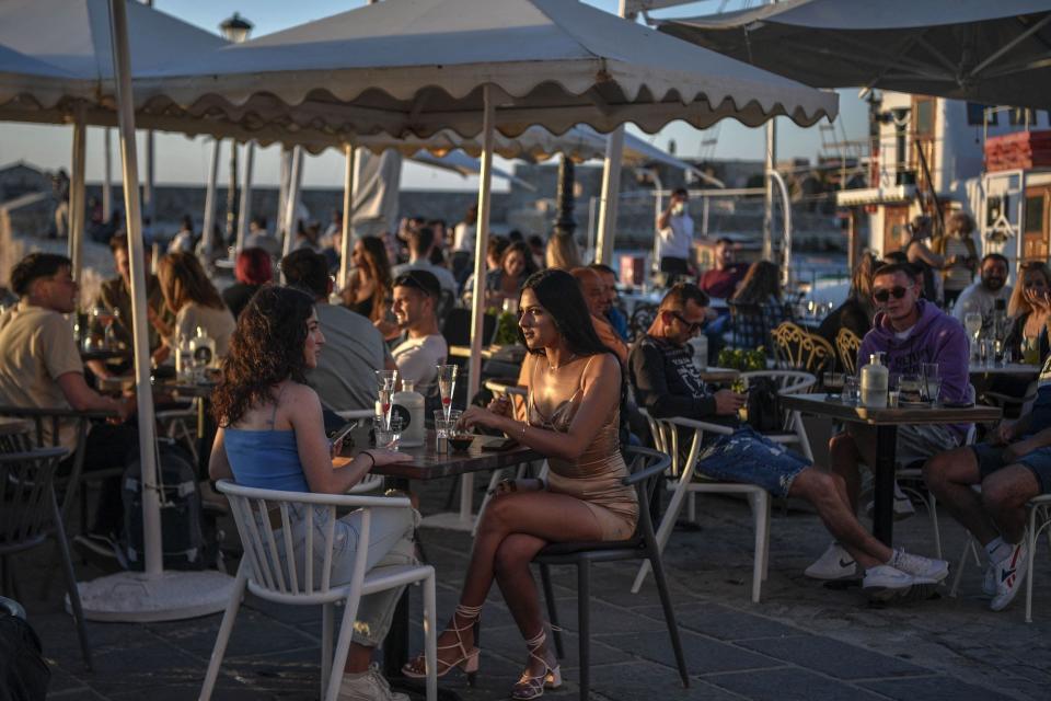 People sitting in a crowded outdoor bar/restaurant in Greece.