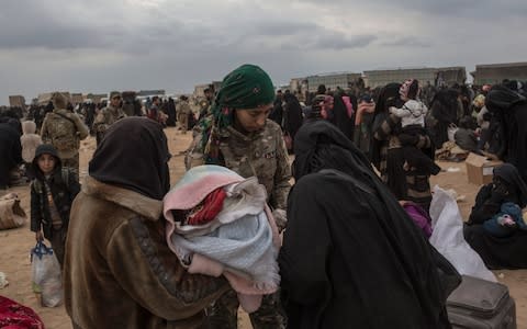 Women wait to board lorries taking them out of the last patch of Islamic State territory in Baghouz - Credit: Sam Tarling, The Telegraph