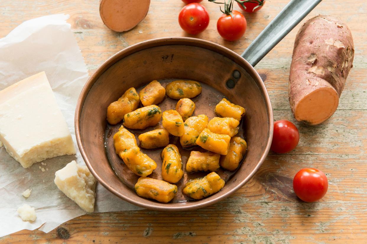 Sweet potato gnocchi with brown butter and sage in a copper skillet surrounded by ingredients