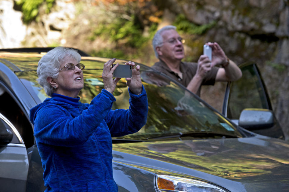 On a cross -country driving tour of national parks, Mary and Bob Barker from New Jersey take a few pictures of the closed gate of Mount Rainier National Park in Washington on Oct. 15, 2013 as the it remained closed due to the partial government shutdown. "It's been nothing but a ghost town at every park we've been too. We thought it (the shutdown) was only going to last a couple of days," said Bob Baker. (AP Photo/The News Tribune, Dean J. Koepfler)