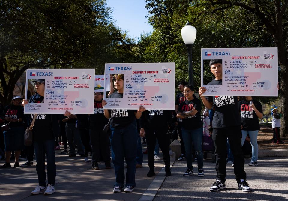 Protesters hold signs designed to look like driver's licenses while listening to speakers Saturday at the Capitol calling for the immediate end of Operation Lone Star. The protesters also demanded driver's licenses for all Texans. Several hundred people rallied and then marched through downtown Austin to Republic Square.