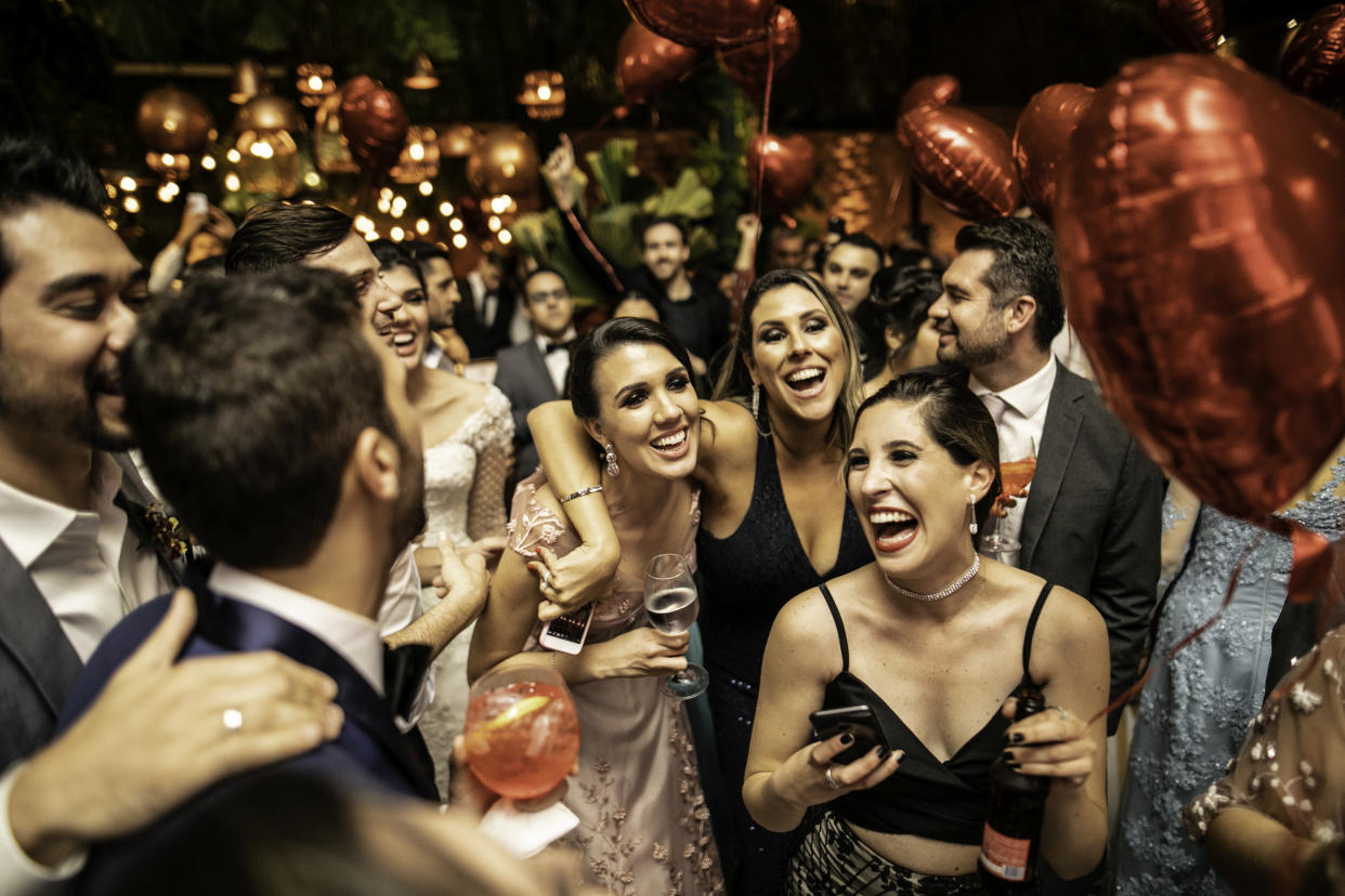 Groom and wedding guests laughing during party as we reveal what to wear to a wedding