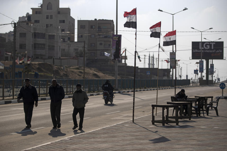 Palestinians walk past Egyptian flags on the side of a street in Beit Lahiya, northern Gaza Strip, Jan. 25, 2022. After years of working behind the scenes as a mediator, Egypt is taking on a much larger and more public role in Gaza. In the months since it brokered a Gaza cease-fire last May, Egypt has sent crews to clear rubbled and promised to build vast new apartment complexes, and billboards of its president Abdel-Fattah el-Sissi, are a common sight. (AP Photo/Khalil Hamra)